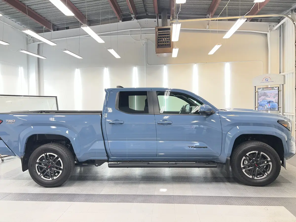 Blue Toyota Tacoma before window tinting, factory glass (view 1)