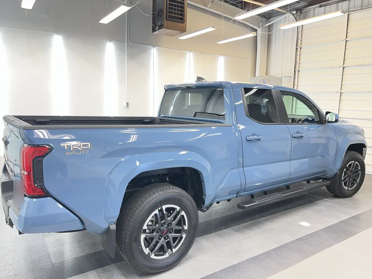 Blue Toyota Tacoma before window tinting, factory glass (view 2)