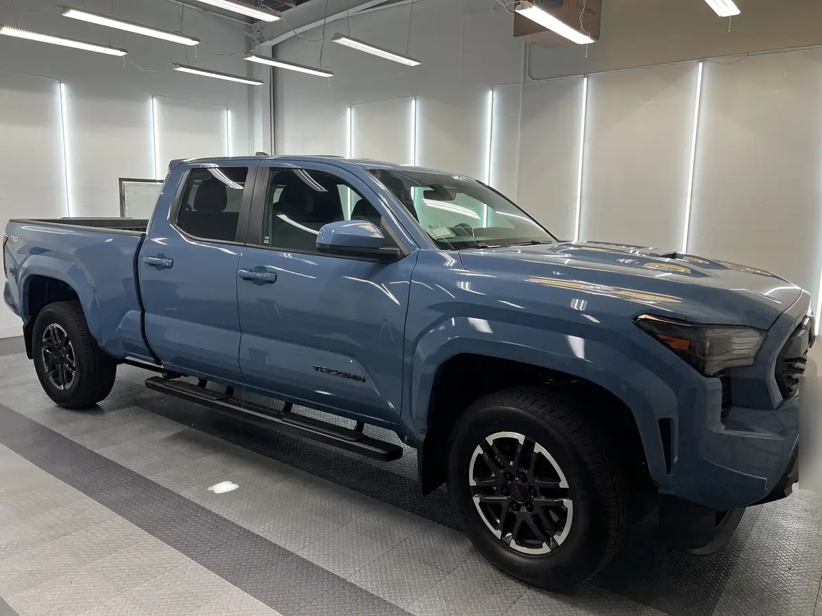 Blue Toyota Tacoma before window tinting, factory glass (view 3)