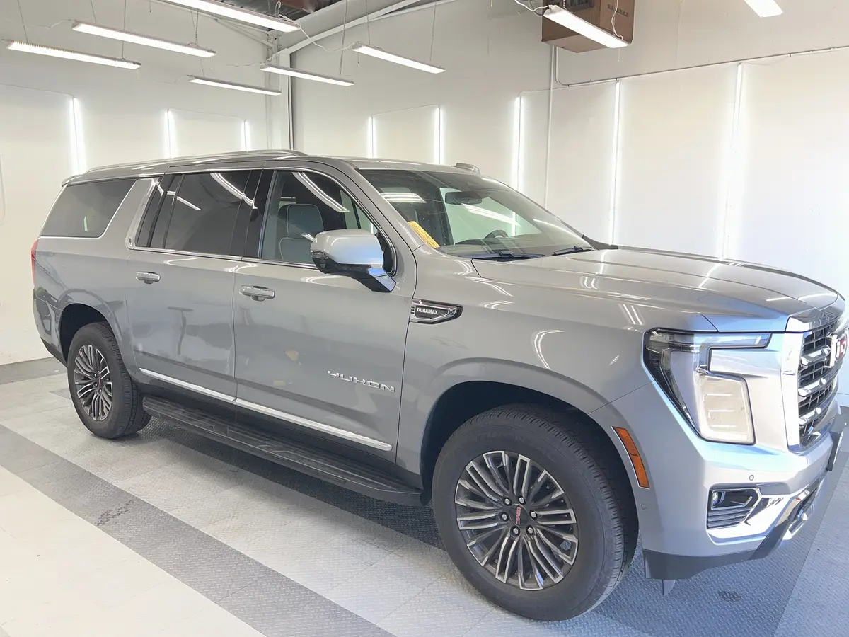 Silver GMC Yukon before window tinting, factory glass (view 1)