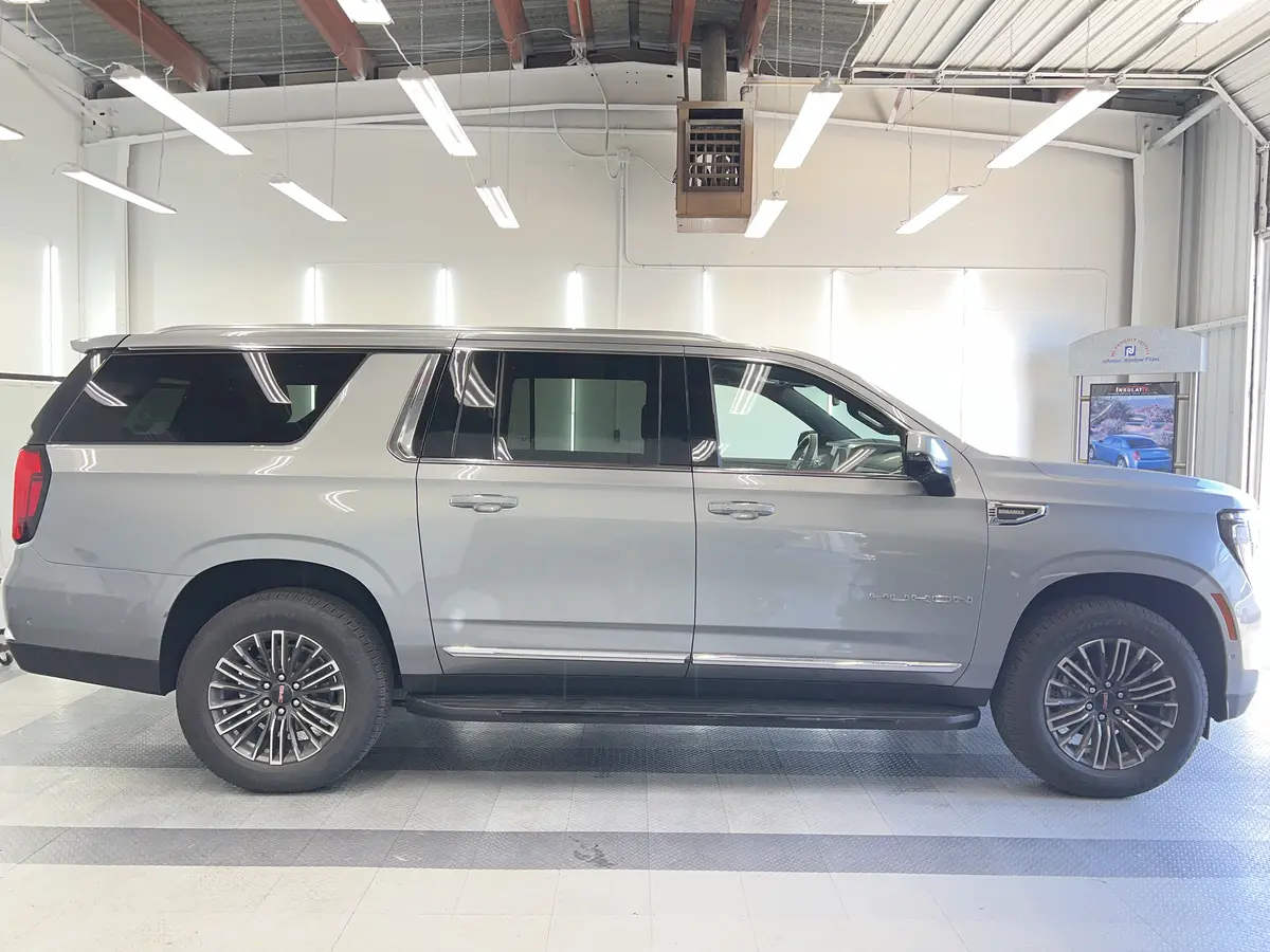 Silver GMC Yukon before window tinting, factory glass (view 2)
