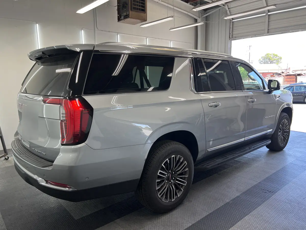 Silver GMC Yukon before window tinting, factory glass (view 3)