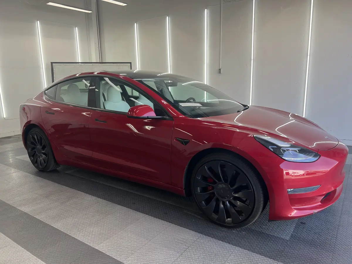 Red Tesla Model 3 before window tinting, factory glass (view 1)