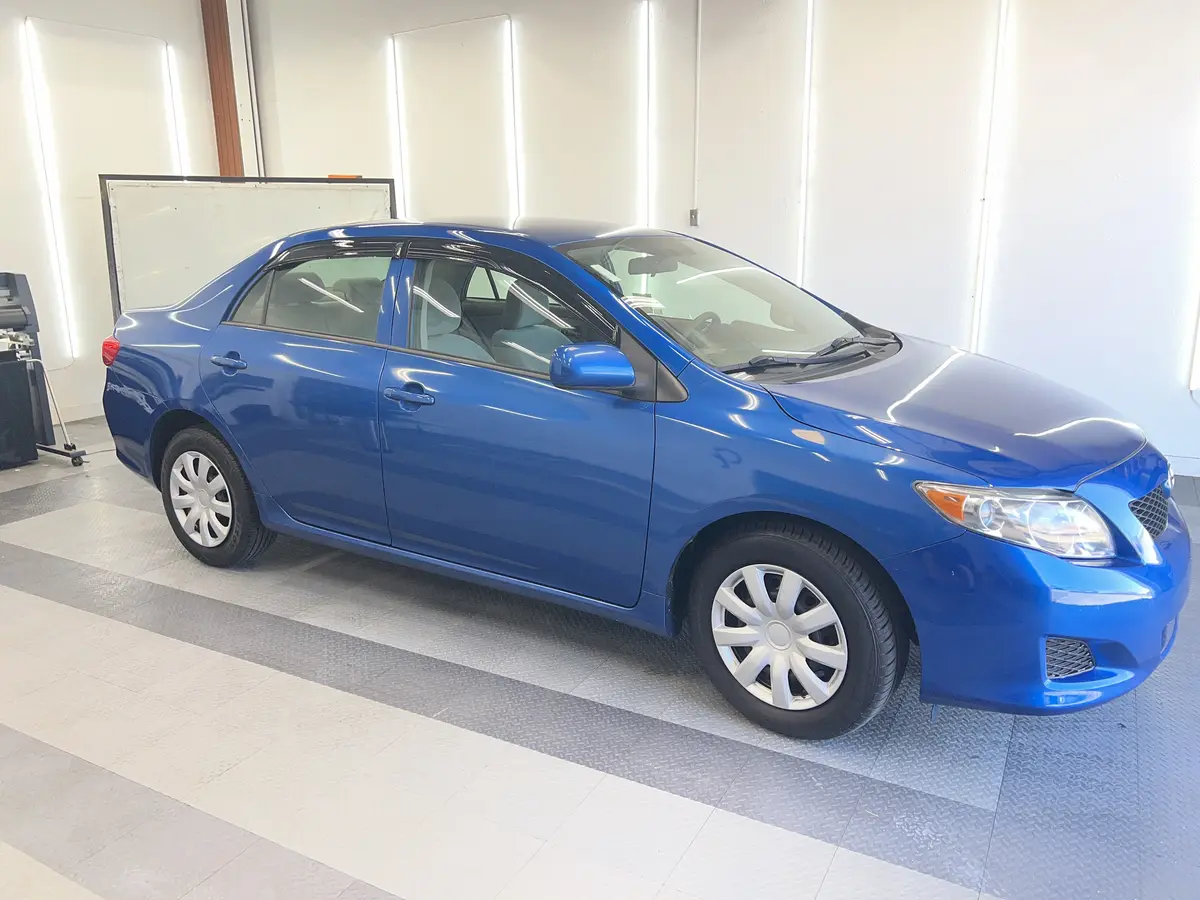 Blue Toyota Corolla before window tinting, factory glass (view 1)