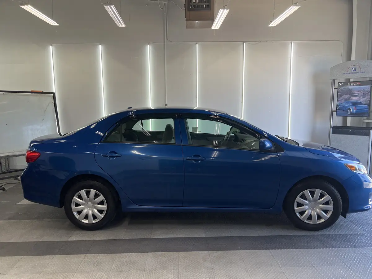 Blue Toyota Corolla before window tinting, factory glass (view 2)