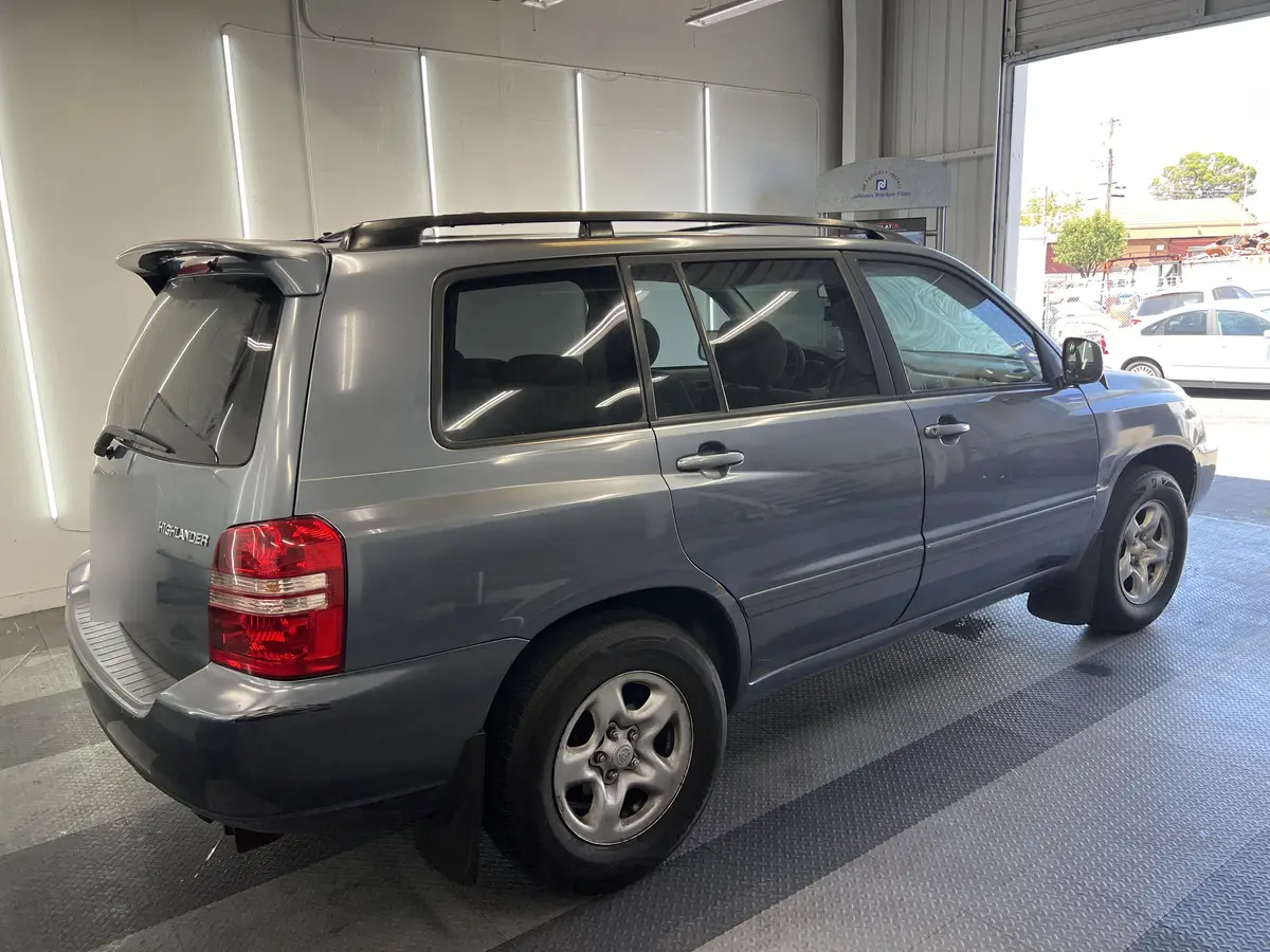Gray Toyota Highlander before window tinting, factory glass (view 2)
