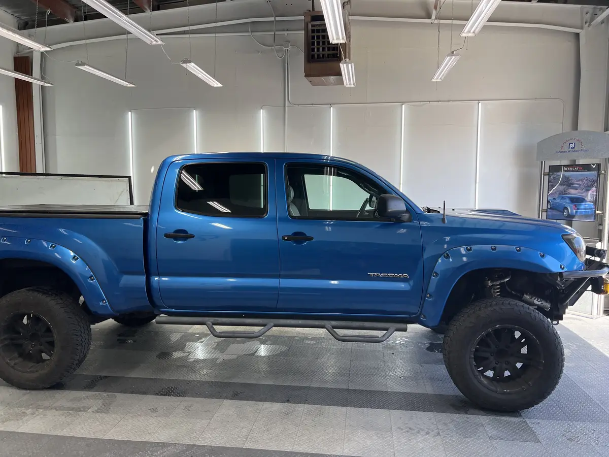 Blue Toyota Tacoma before window tinting, factory glass (view 1)