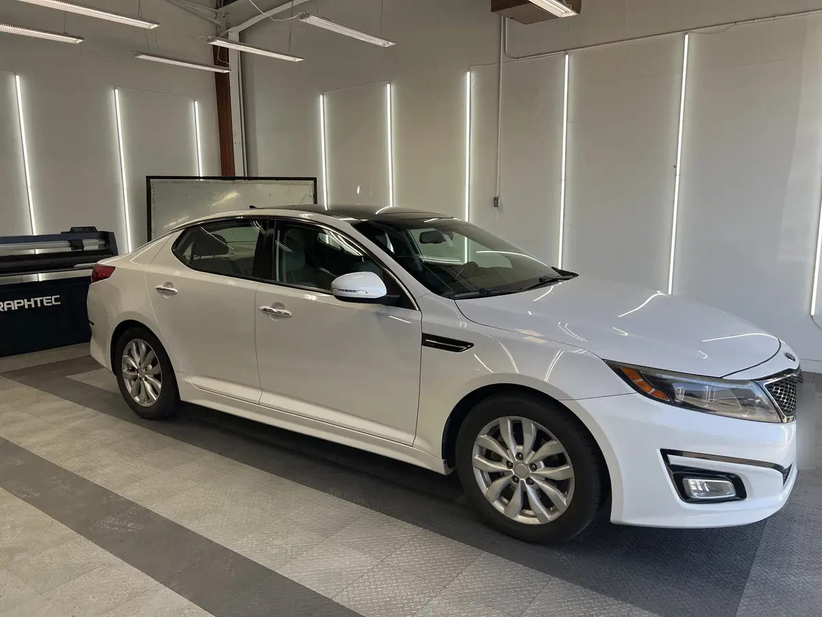 White Kia Optima before window tinting, factory glass (view 1)