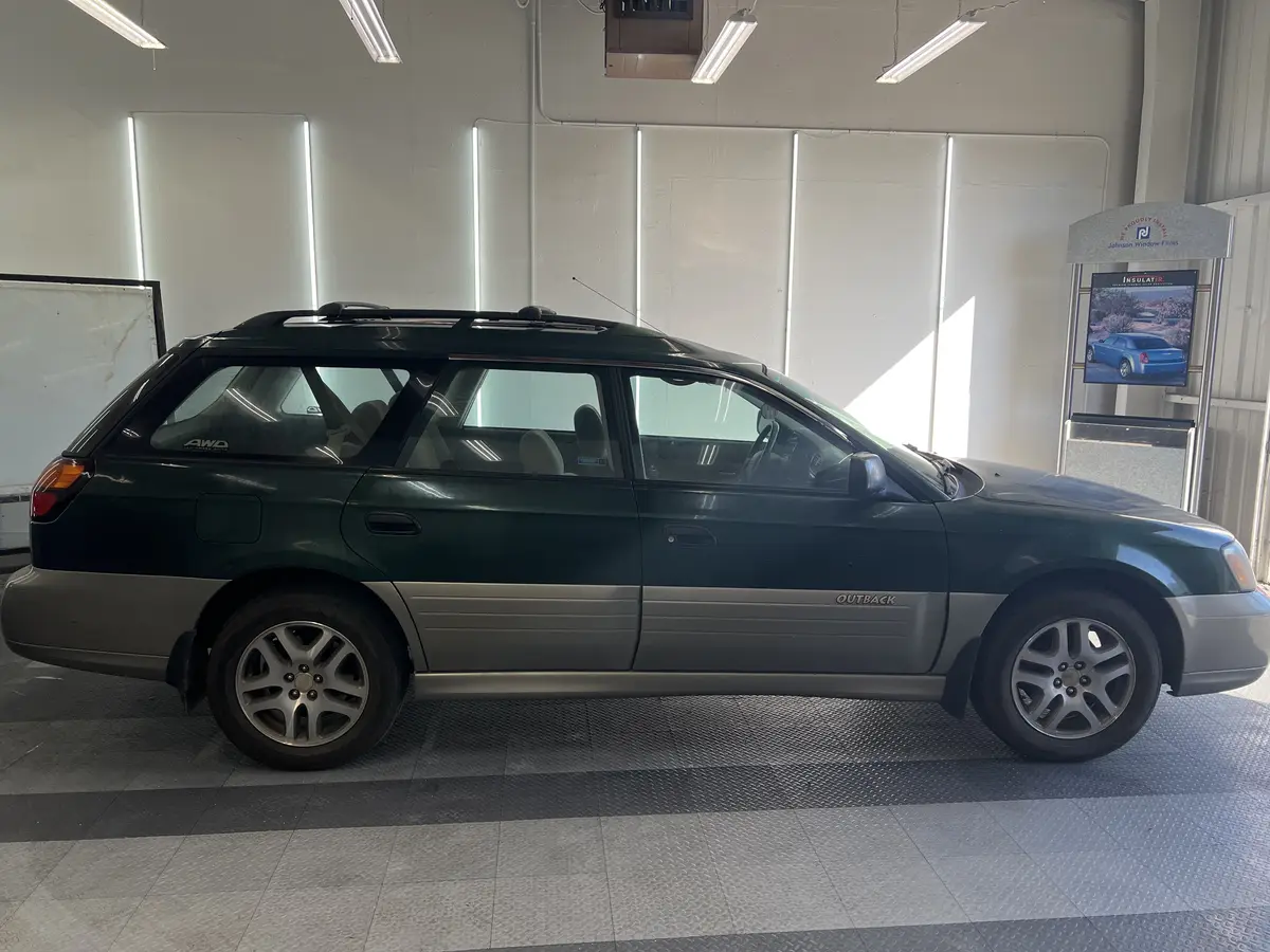 Green Subaru Outback before window tinting, factory glass (view 2)
