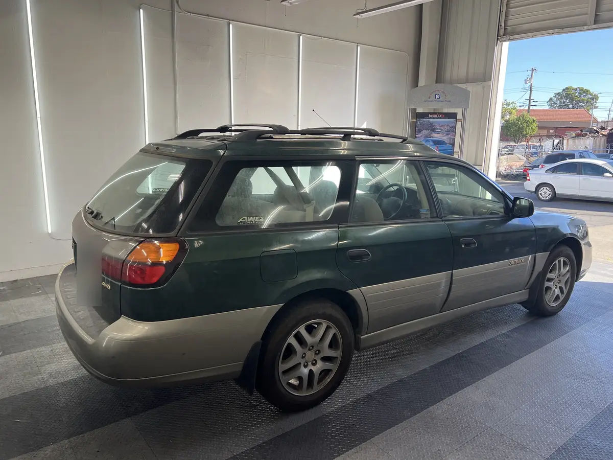 Green Subaru Outback before window tinting, factory glass (view 3)