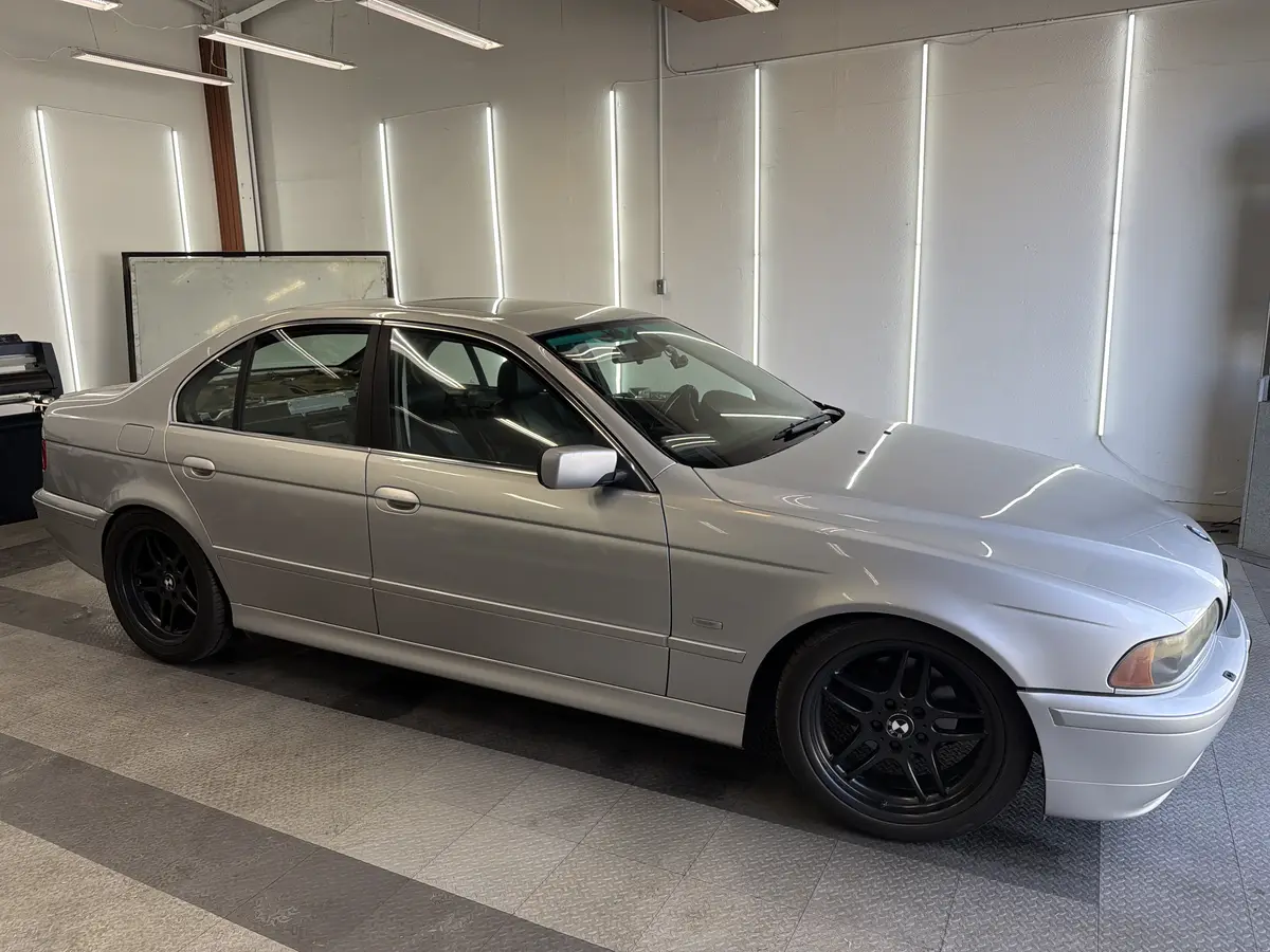 Silver BMW 5 Series before window tinting, factory glass (view 1)