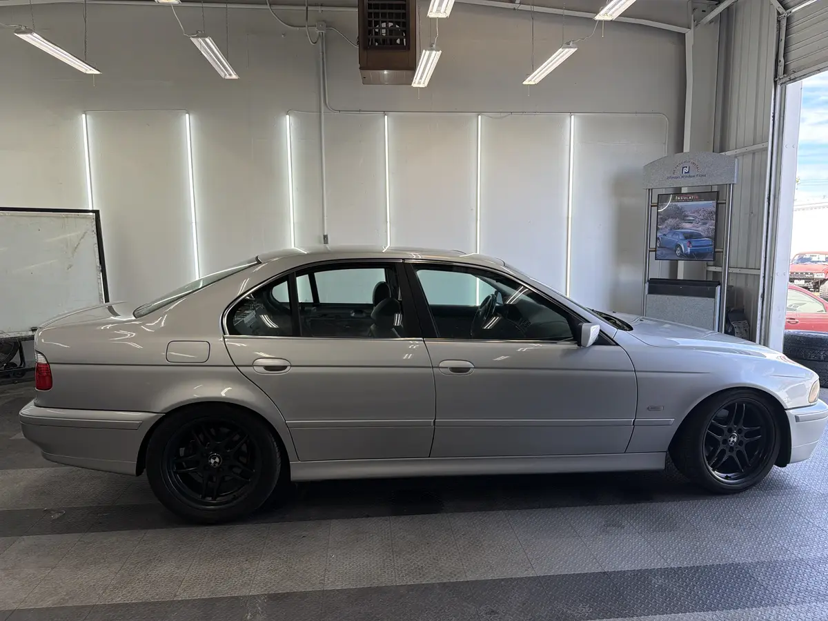 Silver BMW 5 Series before window tinting, factory glass (view 2)