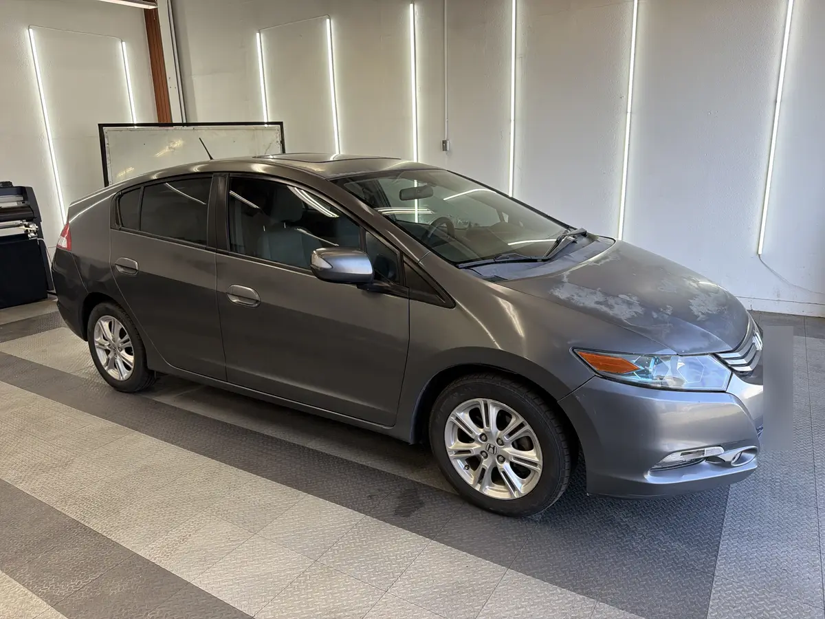 Gray Honda Insight before window tinting, factory glass (view 1)