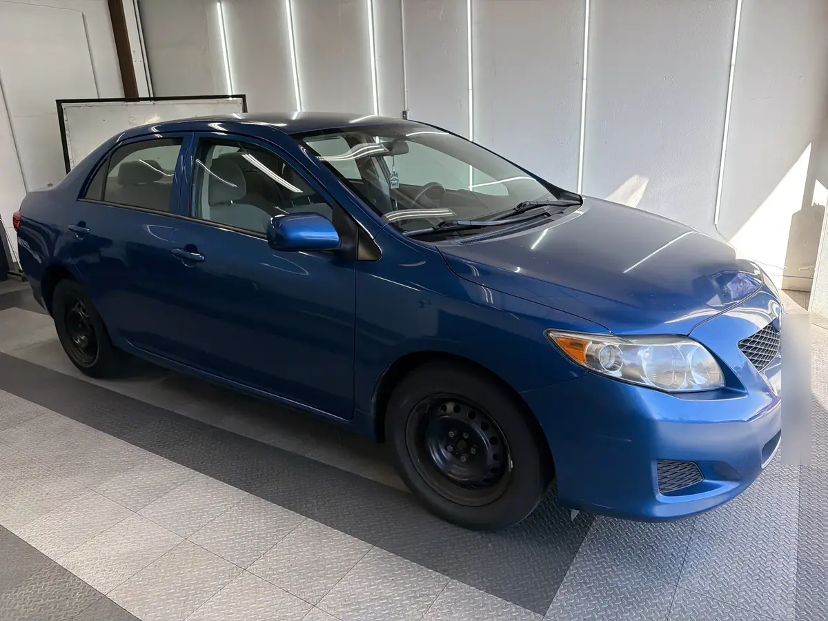 Blue Toyota Corolla before window tinting, factory glass (view 1)