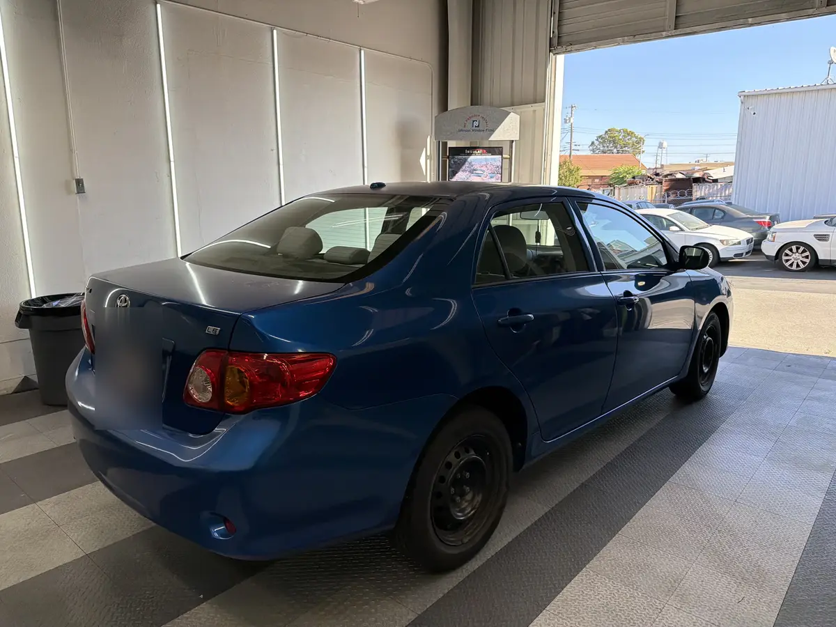 Blue Toyota Corolla before window tinting, factory glass (view 3)
