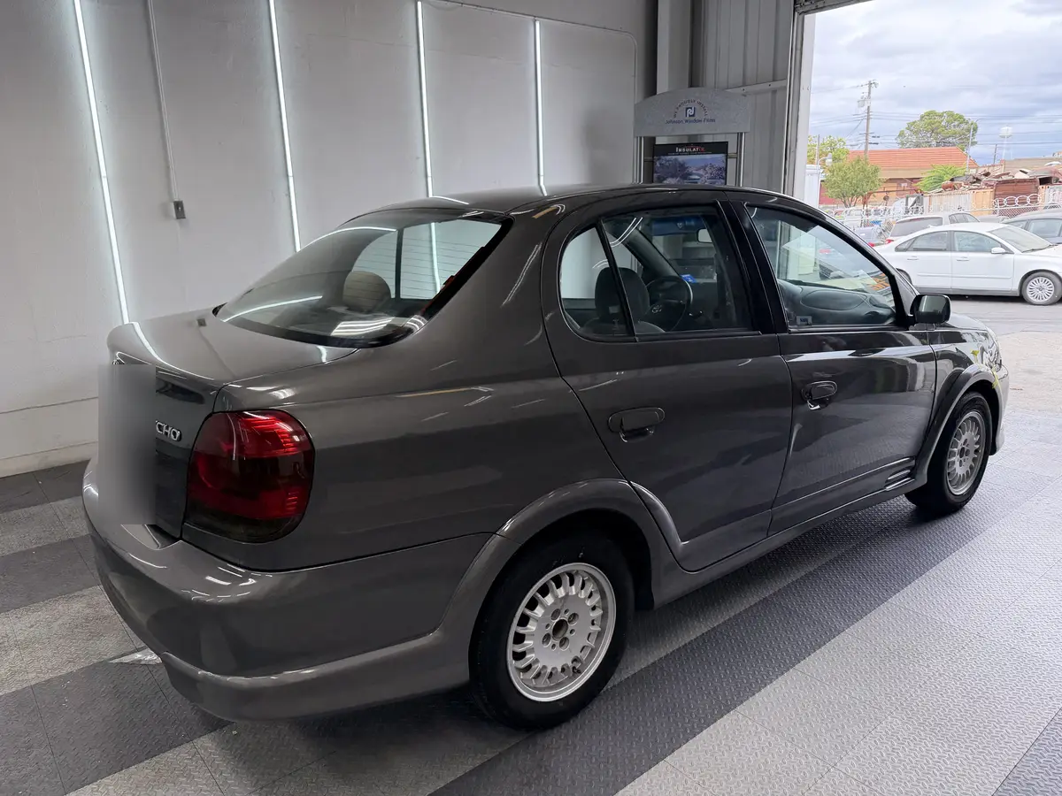 Gray Toyota Echo before window tinting, factory glass (view 3)