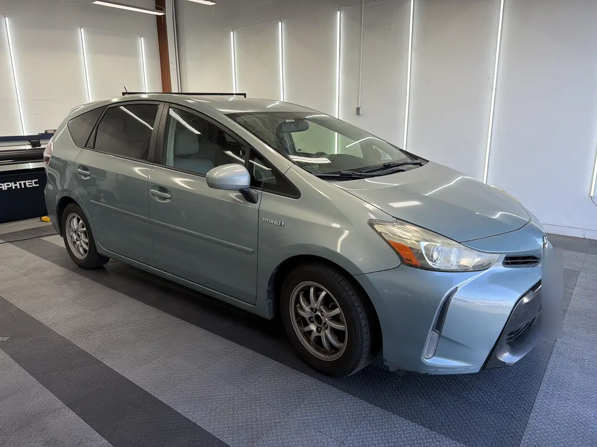 Blue Toyota Prius v before window tinting, factory glass (view 1)