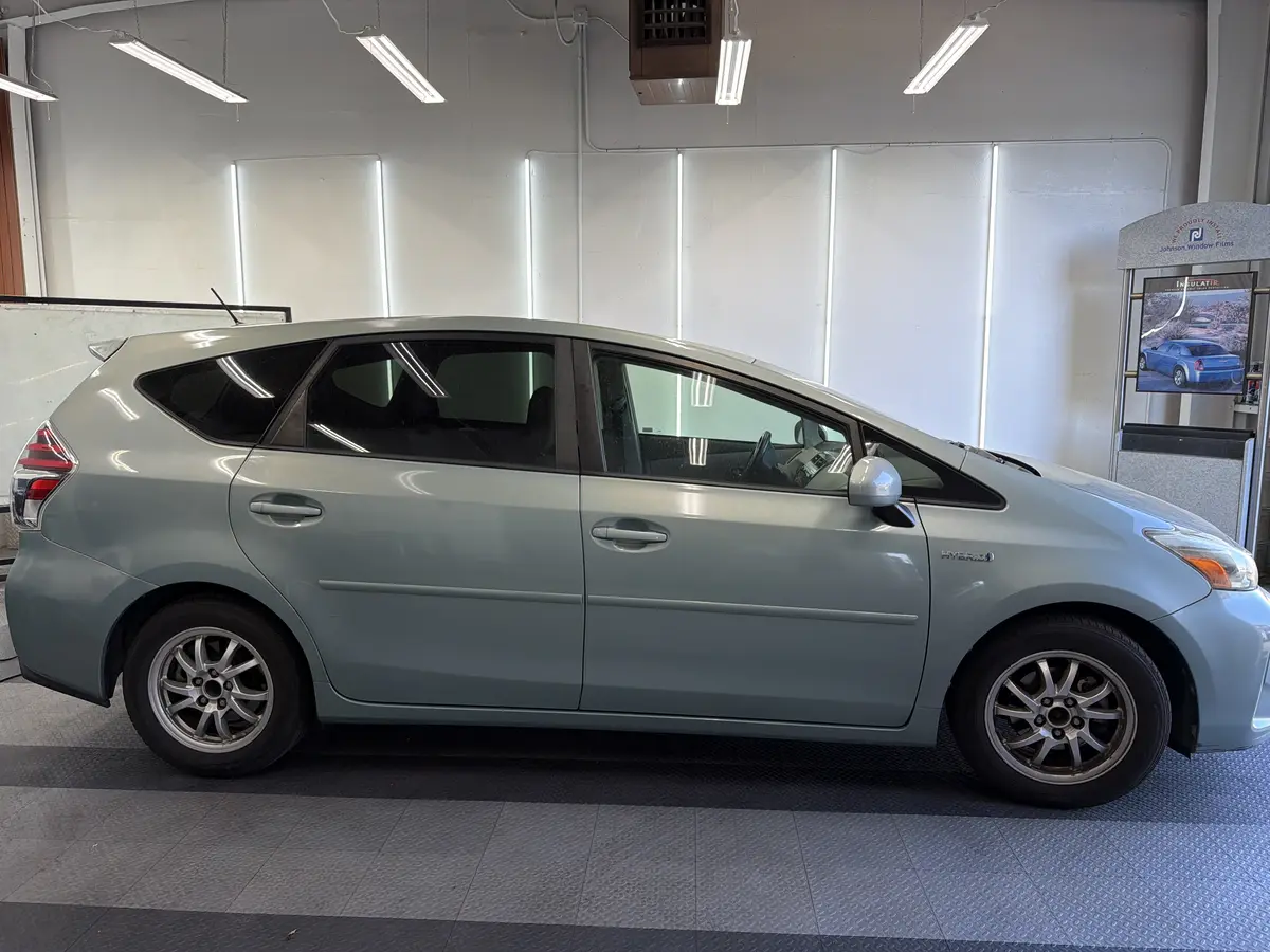 Blue Toyota Prius v before window tinting, factory glass (view 2)