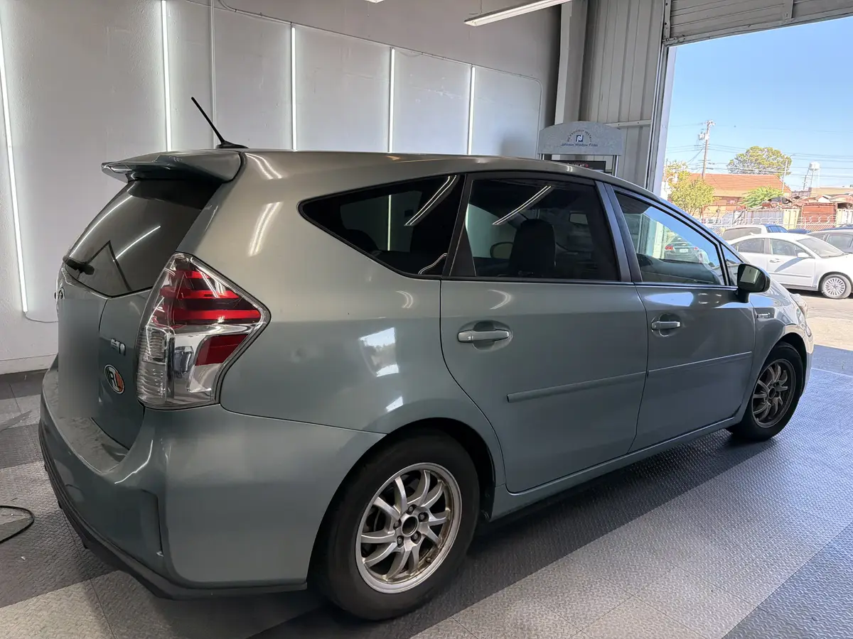 Blue Toyota Prius v before window tinting, factory glass (view 3)